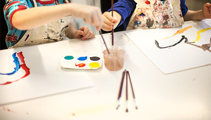 Händer på barn som målar med vattenfärger