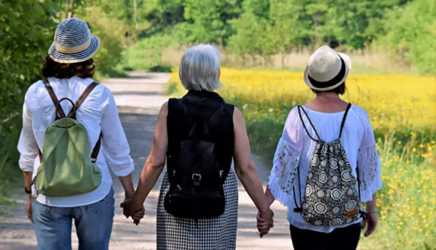 Tre kvinnor på promenad på en liten väg i sommartid.
