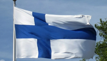 Finlands flagga som fladdrar på en flaggstång med en blå himmel i bakgrunden