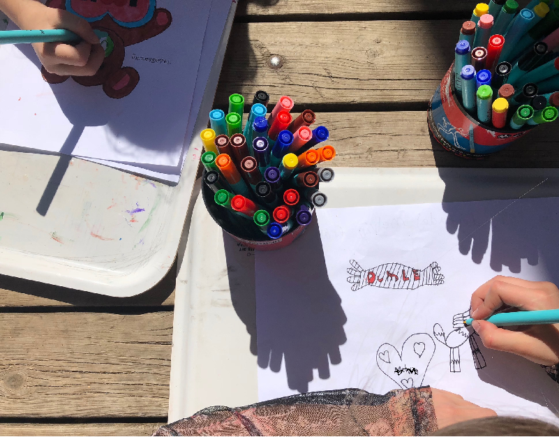 Barnhänder som målar teckningar med färgpennor