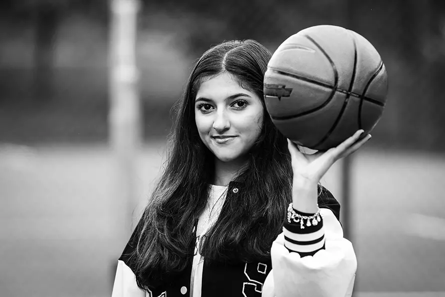 Dorsa håller en basketboll i sin ena lyfta hand.