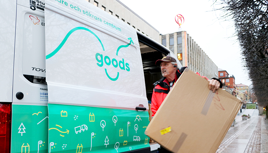 Transportör bär ut ett paket ur fordonet som används till Good Goods