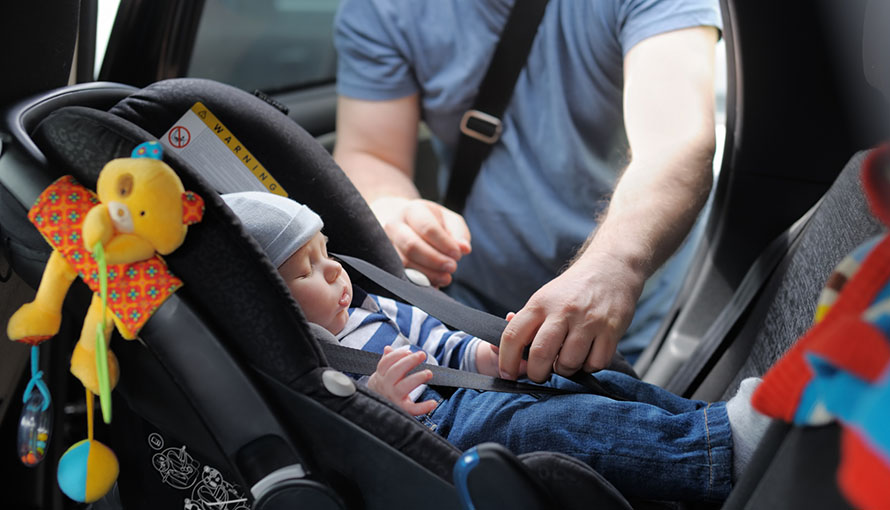 Förälder som spänner fast sitt barn i en bilbarnstol 