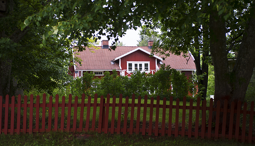 Röd villa i en lummig trädgård.