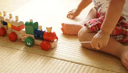 Ett litet barn som leker med ett tåg i trä.