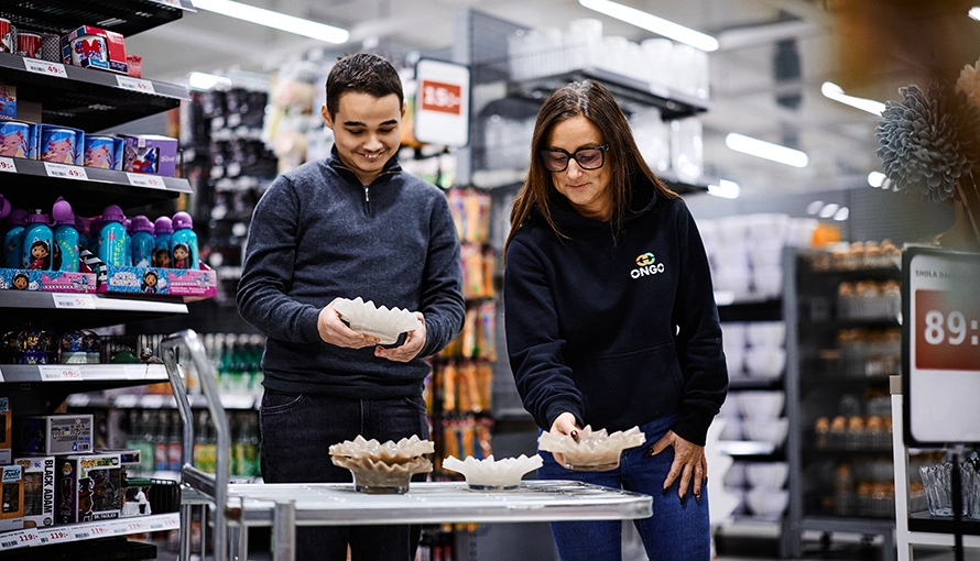 APL-handledare (butik) och elev står i en butik och plockar upp varor.