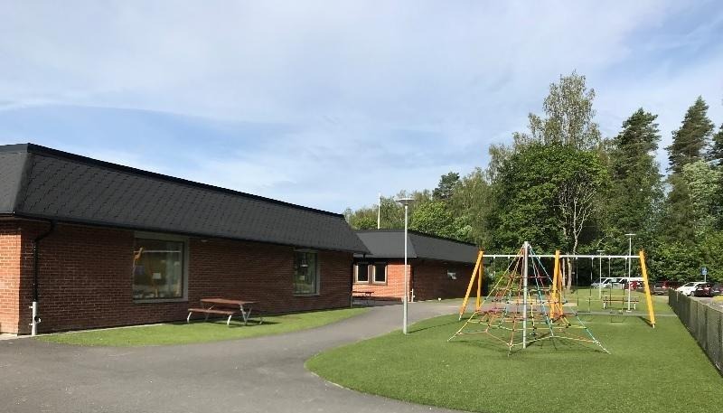 Björkhöjdskolans byggnad samt en del av skolgården med en klätterställning.