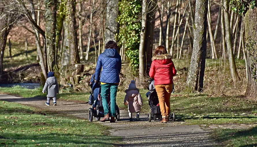 Vuxna som går på en grusväg i skogen med några små barn.