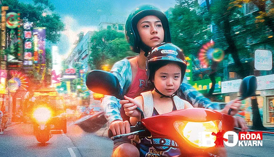 Litet barn sitter framtill på moped som körs av hennes unga mamma på trafikerad gata