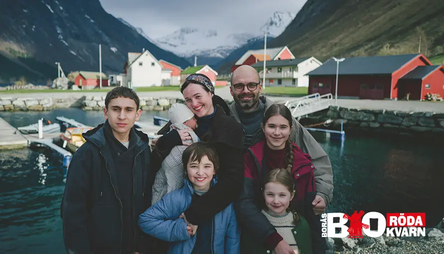 Gladlynt familj framför ett mäktigt berg vid norsk kuststad