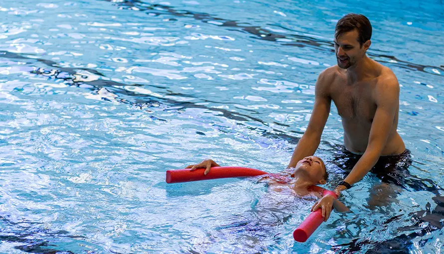Personal håller i simskola med ett barn
