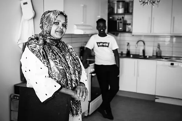 Suaad står framför köket. I bakgrunden ser vi hennes son.