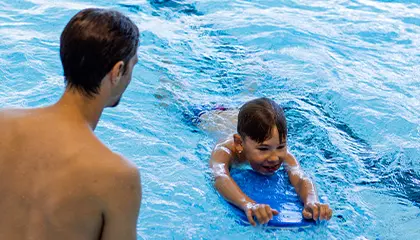 Barn som är i bassäng och får simundervisning av vuxen person