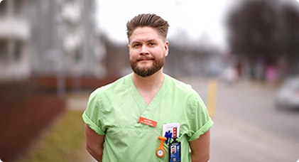 Anton Carlsson, sjuksköterska, ljushårig man i grön arbetsrock. 