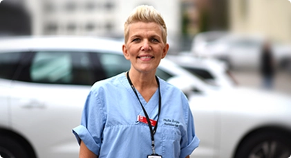 Lena Broberg, specialistutbildad palliativ-sjuksköterska, ljuhårig kvinna i ljusblå arbetskläder. 