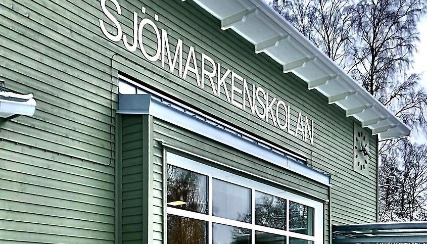 Sjömarkenskolans fasad med en skylt med skolnamnet på.