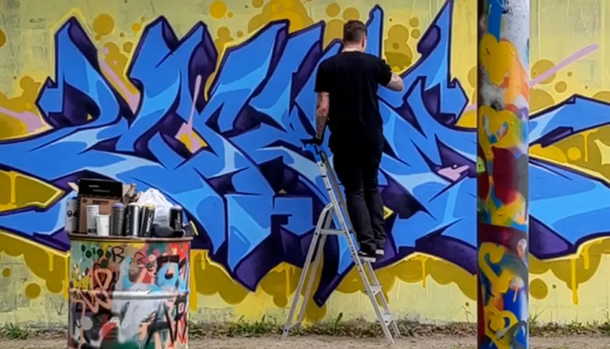 Person står på stege och målar graffiti.