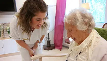 Omvårdnadspersonal pratar med äldre kvinna.