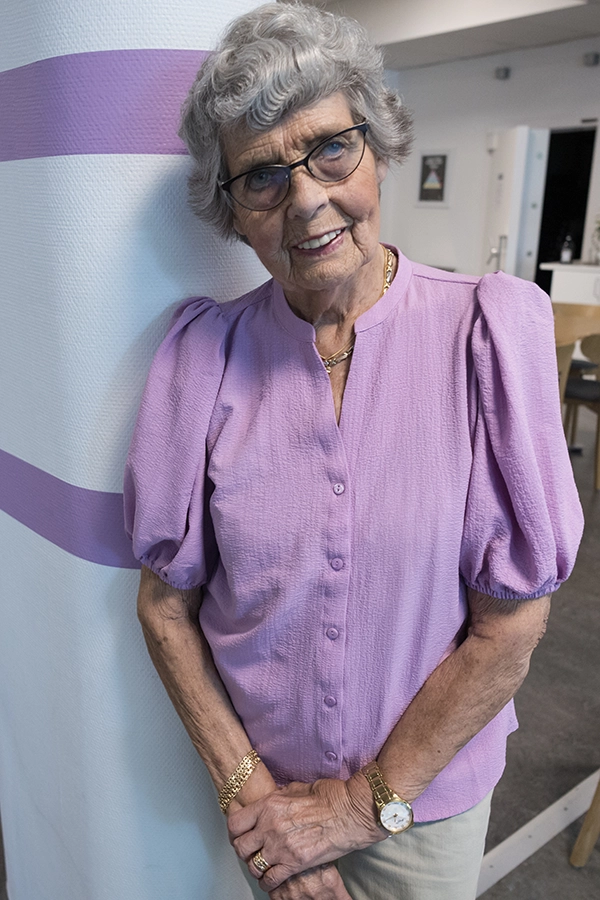 Ett porträtt på Marjatta Nerman som står vid en stolpe med händerna framför sig.