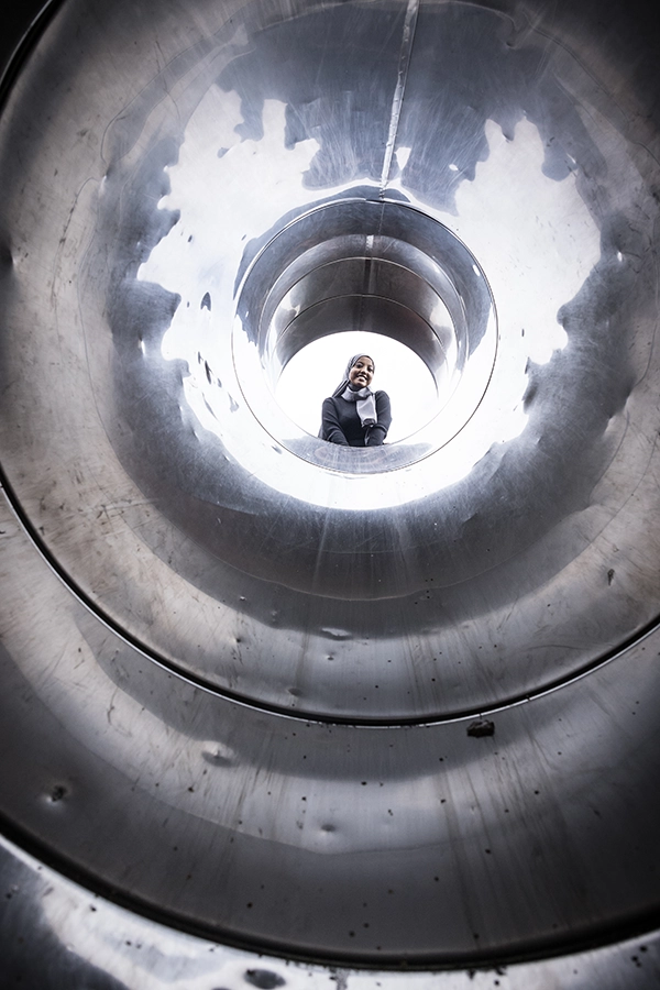 Rumesa Hamed är längst upp i en tunnelrutschkana och tittar neråt. Bilden är tagen från slutet av rutschkanan och uppåt i tunneln. 