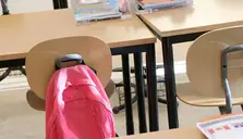 En skolryggsäck som hänger på en stol 