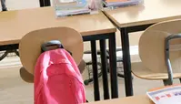 En skolryggsäck som hänger på en stol 
