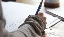 En hand som skriver på ett papper