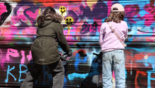 Två barn bakifrån målar med graffiti