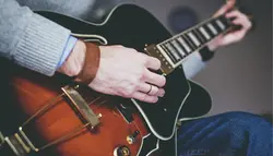 En person spelar en brun gitarr