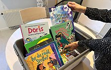 En låda med olika barnböcker på ett kapprumsbibliotek i Fristad. 