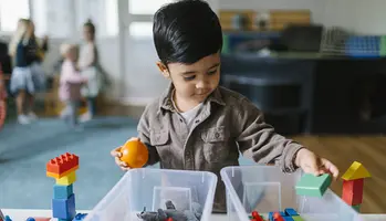 Ett barn som leker med leksaker vid ett bord