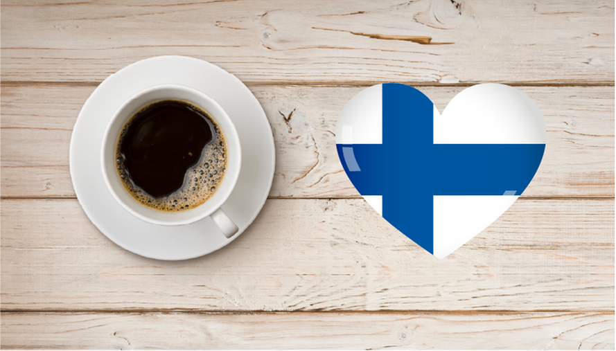 Kaffe kopp på ett bort av trä och ett illustrerat hjärta med Finlands flagga