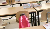 Stolar i ett klassrum. Det hänger en rosa ryggsäck på stolen. 