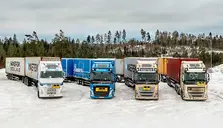 Fyra långa lastbilar vid sidan av varandra i ett snötäckt landskap. Foto: Anna Sigge
