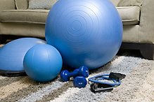 En bild med olika träningsredskap, pilatesboll, gummiband, hantlar m.m.